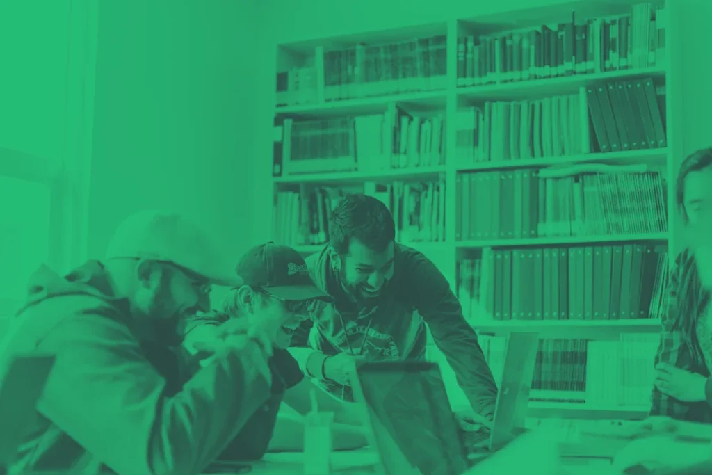 Plusieurs personnes travaillent ensemble autour d’ordinateurs portables dans une bibliothèque.